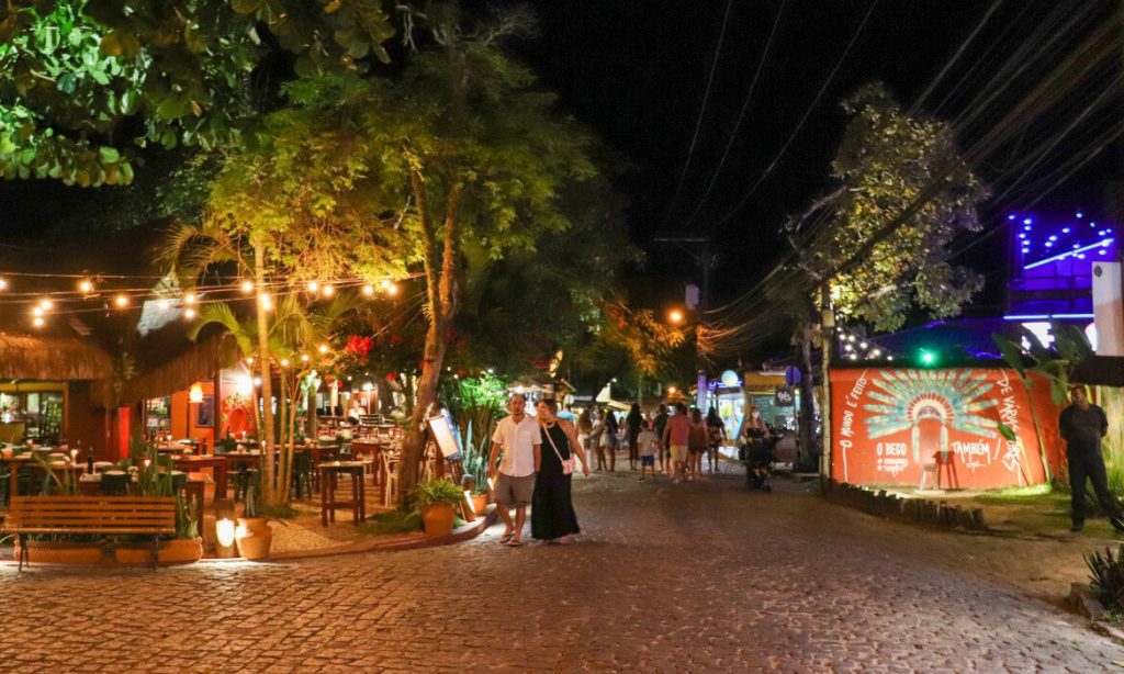 imagem ilustra a rua bróduei, localizada em Arraial dAjuda. Mostra a rua movimentada a noite com os restaurantes e apresenta a gastronomia da região. Conheça o sagui boutique hotel